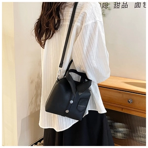 Close-up of black shirt-shaped cross-body bag with lychee texture and button detail