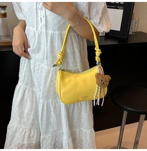Detail van de gele lederen hobo-tas met geknoopte riem en bruine pluche beer hanger