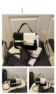 Detail of minimalist black and white square bag with golden turn-lock and pebbled texture
