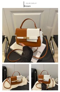 Detail of color-block Kelly bag showing brown and white leather with gold twist lock closure