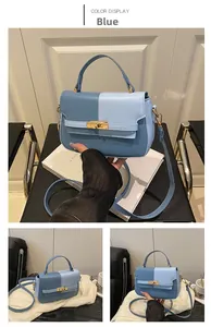 Detail of blue color-block handbag showing golden twist-lock and slim leather strap