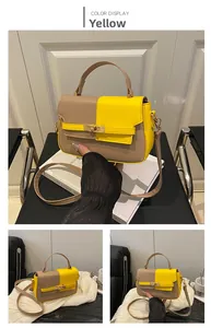 Detailed view of bicolor square handbag with golden twist lock and yellow-brown patchwork