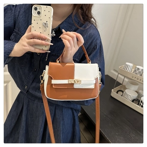 Detail of color-block brown and white leather Kelly bag with metal buckle and shoulder strap