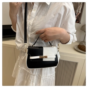 Detail shot of a black and white contrast leather crossbody bag with gold hardware