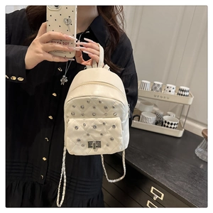 Détail du mini sac à dos matelassé crème avec clous argentés et bandoulière en chaîne