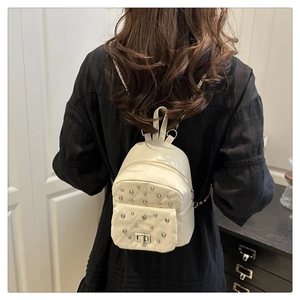 Detail of cream mini backpack featuring diamond quilted faux leather and silver studs