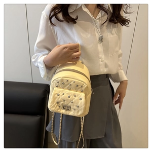 Detail eines hellgelben Mini-Rucksacks mit Rautensteppung, Strass und Metallkette
