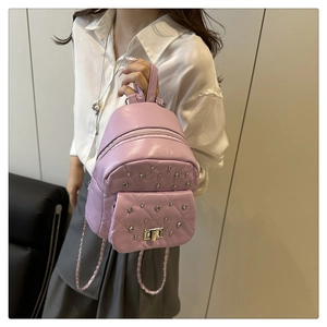 Side view of a mini purple quilted backpack with silver rivets and chain straps on model