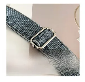 Detail der verstellbaren Silberschnalle und des blauen Denim-Gurts einer Schultertasche