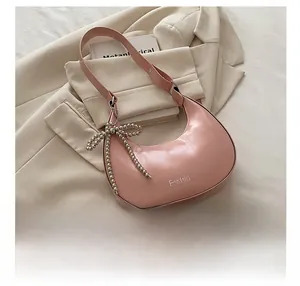 Détail du sac hobo rose brillant avec breloque nœud perlé argenté et logo mode