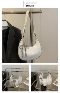 Détail du sac à bandoulière blanc en demi-lune avec imprimé Fashion et pendentif nœud argenté