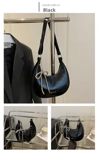 Détail du sac demi-lune noir verni avec nœud en perles argentées et large bandoulière