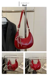 Détail d'un sac hobo en cuir verni rouge avec nœud en perles et logo de mode
