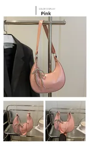 Détail du sac hobo rose avec pendentif nœud métallique et inscription Fashion élégante