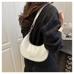 Close-up of white crescent crossbody bag with adjustable strap and fashion print