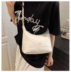 Close-up of white embossed hobo bag with gold adjustable buckle and logo lettering