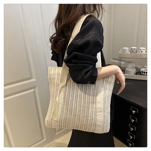 Detail of woven straw tote bag with elegant side tassel and canvas strap for women