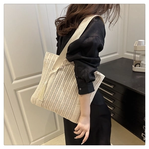 Detail view of woven tote bag showing hollow knit texture and minimalist tassel charm