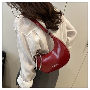 Detail view of red patent leather crescent bag with silver beaded chain decoration