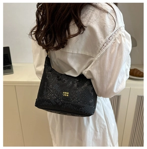 Fashionable black faux snakeskin mini shoulder bag with gold lettering shown on model