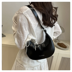 Detail of black glossy patent leather hobo bag with silver bead chain and Fashion text