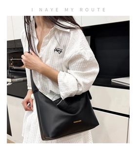 Détail d'un sac cabas minimaliste en cuir noir mat avec lettrage doré sur chemise
