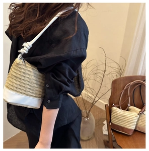 Detail of woven straw bucket bag with white leather base and knot shoulder strap detail