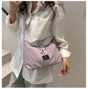 Close-up of minimalist lavender nylon crossbody bag with black woven logo and dual zippers