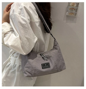 Close-up of grey nylon crossbody bag on model showing large capacity and zipper detail