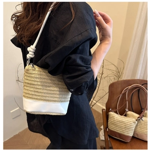Detail of woven straw bucket bag showing white leather base and knot shoulder strap