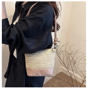 Detail of hand-woven straw bucket bag with smooth leather base and zip closure