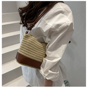 Detail of woven straw shoulder bag with brown leather base and unique knotted strap design