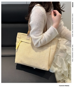 Detail of beige corduroy tote bag featuring a front zipper pocket and woven shoulder strap