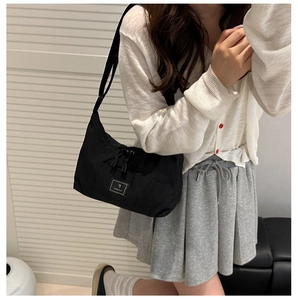 Detail of black nylon shoulder bag with adjustable strap and square logo patch