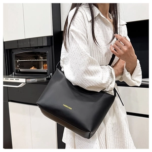 Vue détaillée du grand sac cabas noir avec lettrage doré et bandoulière large élégante