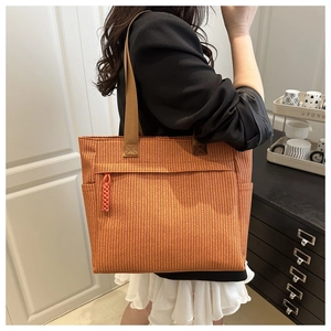 Detail van oranje geweven shopper met ritsvak aan de voorkant en gevlochten ritstrekker