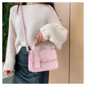 Detailed view of pink leather crossbody bag with fashion tag and matching shoulder strap