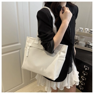 Detail of white tote bag with woven texture, front zipper pocket and side pouch