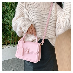 Detail of pink leather handbag showing the curved handle and adjustable crossbody strap