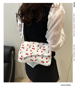 Rear view of a model wearing a white cherry print crossbody bag with golden hardware