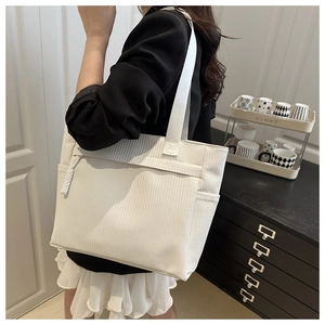 Detail of white textured tote bag with woven rope accent on a professional suit