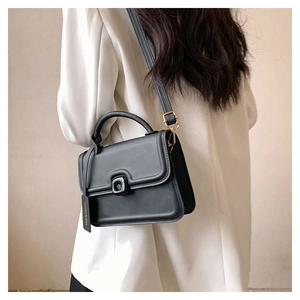 Detail of minimalist black leather crossbody bag with square buckle and adjustable strap