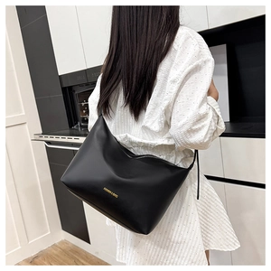 Detail of a large black leather tote bag with gold lettering shown in a stylish home setting