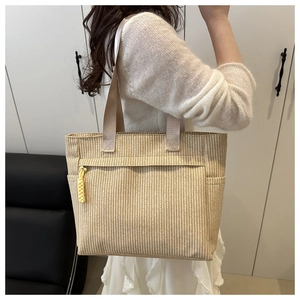 Detail of woven straw tote bag featuring a striped pattern and convenient zipper pocket