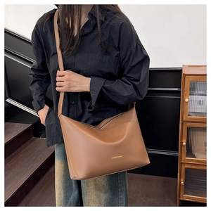 Détail du sac fourre-tout marron caramel avec logo doré et texture en cuir mat lisse
