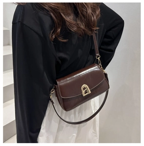 Détail d'un sac bandoulière en cuir marron foncé avec boucle en métal doré chic