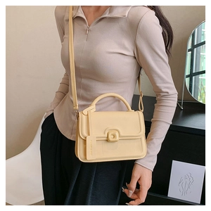 Detailed side view of cream beige flap crossbody bag with top handle and leather strap