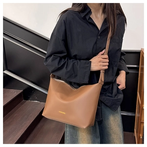 Détail du sac bandoulière marron avec logo doré et bandoulière réglable élégante