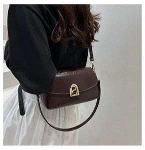 Détail d'un sac bandoulière en cuir marron foncé avec boucle en métal doré
