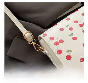 Detailed close-up of golden metal hooks and adjustable buckles on a white cherry bag